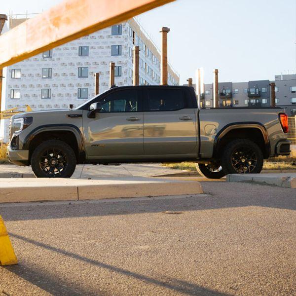 A silver truck parked with large buildings in the background